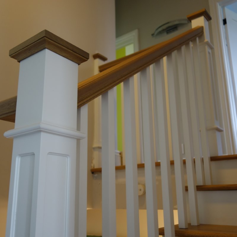 classic white box newel post with stained wood cap and handrail